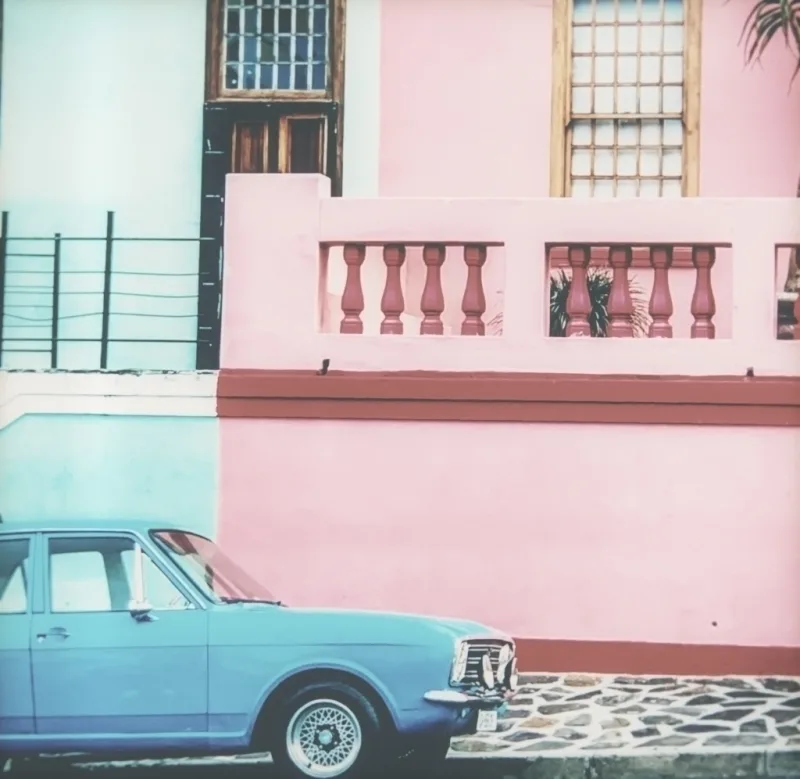 A pastel street with a pale-blue vintage car, on Daylight film